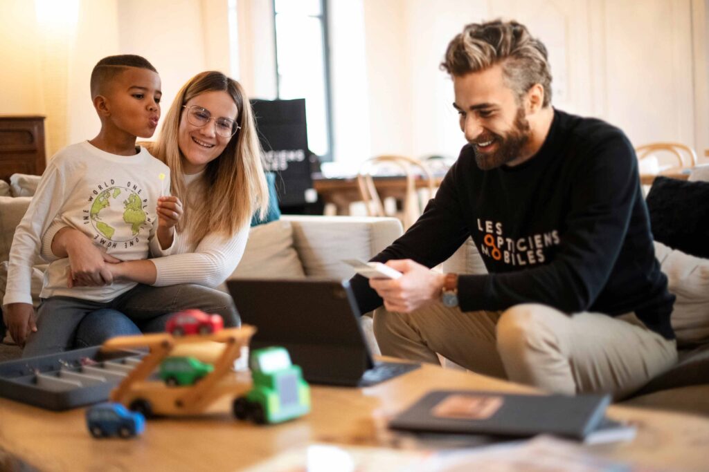 Opticien à domicile du réseau Les Opticiens Mobiles en consultation avec une famille illustrant le service de proximité et l’engagement humain de la franchise