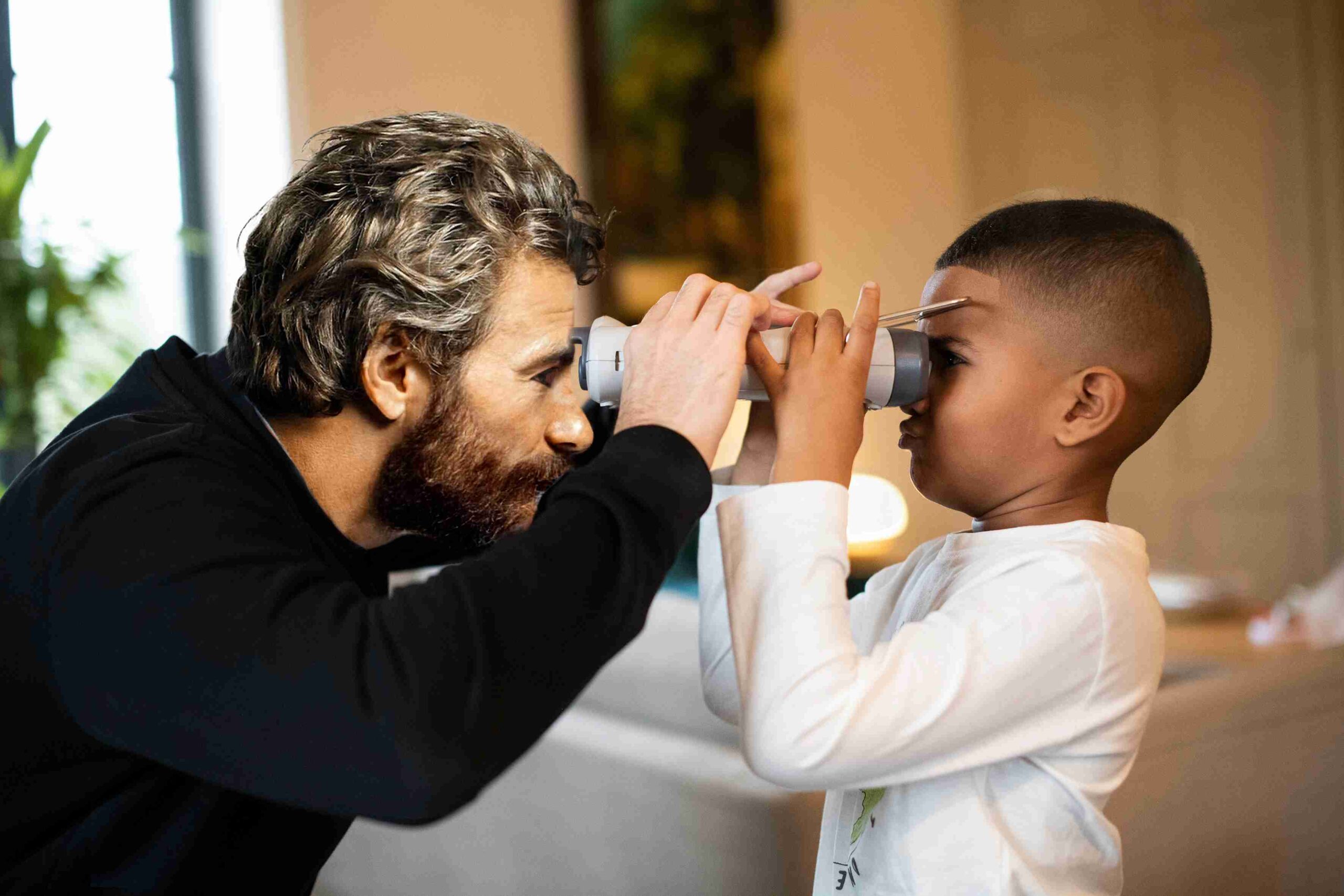 Opticien à domicile épanouis réalisant un examen de vue avec un enfant.