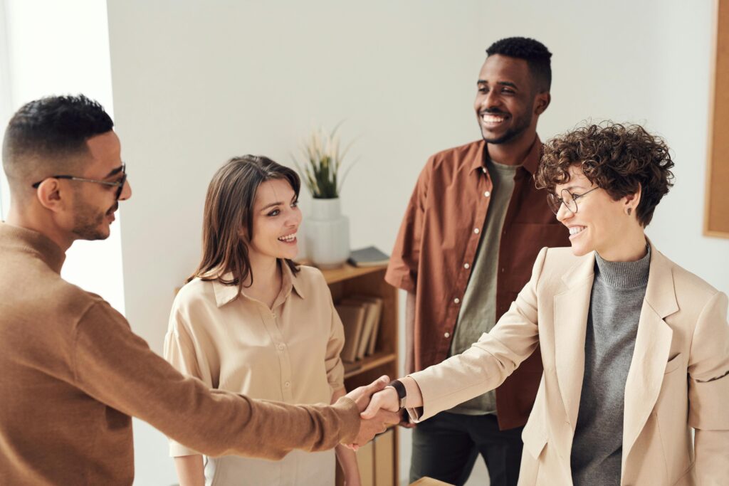 Professionnels lors d'une réunion de réseautage, serrant la main et souriant, illustrant l'importance des relations professionnelles pour le succès d'un opticien à domicile.